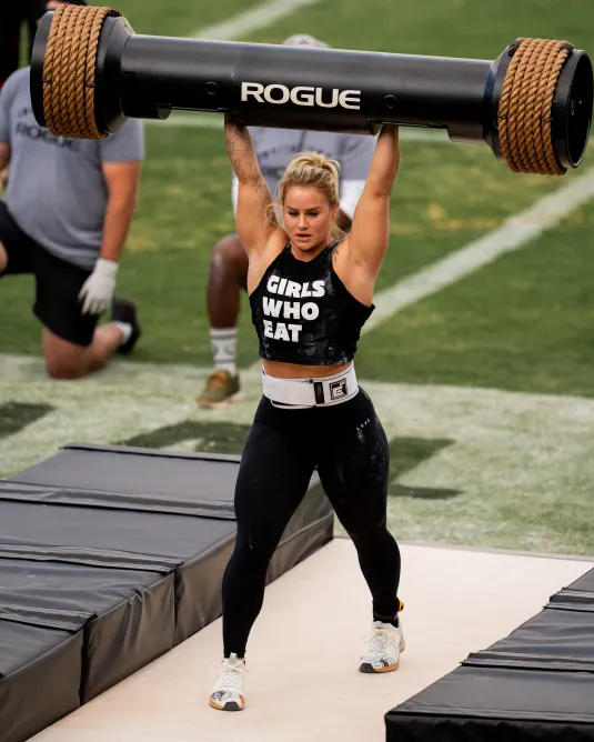 Strong women athlete lifting heavy item overhead showing her strength and skill